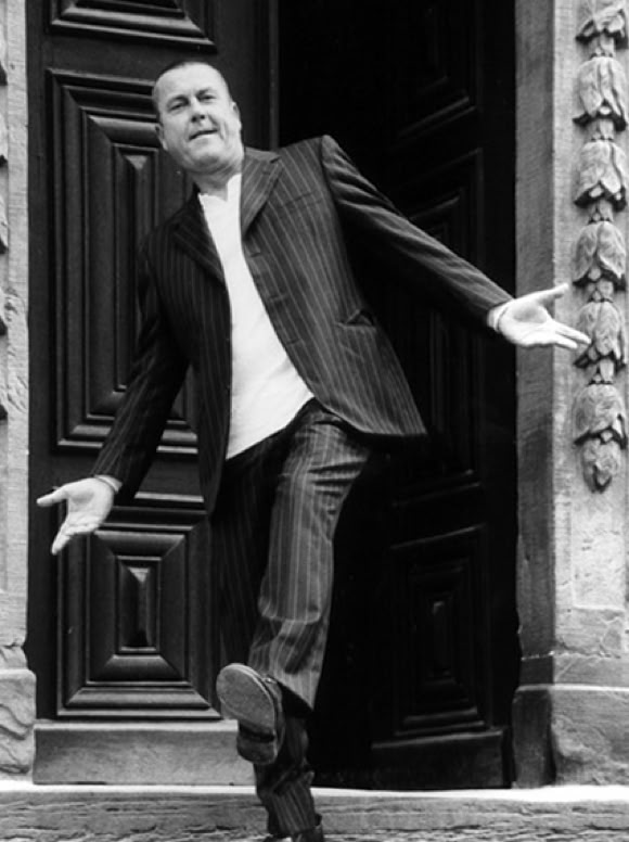 Lutz G&ouml;rner in einem Anzug steht in einer offenen T&uuml;r und gestikuliert mit den Armen.