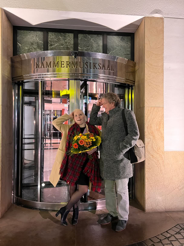 Nadia Singer mit Blumenstrau&szlig; und Lutz G&ouml;rner stehen nach dem Konzert vor dem Eingang zum Kammermusiksaal H.J. Abs im Beethoven-Haus Bonn.