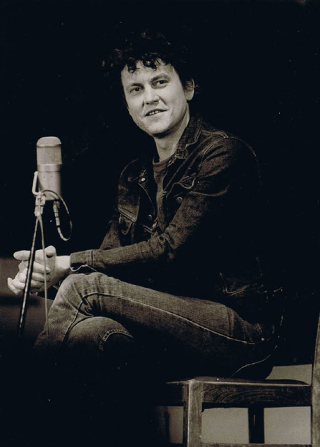 Lutz G&ouml;rner sitzt auf einem Stuhl, tr&auml;gt eine dunkle Jacke und Jeans, h&auml;lt ein Mikrofon in der Hand und schaut zur Seite.